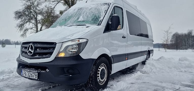 Ośnieżony, biały bus marki Mercedes