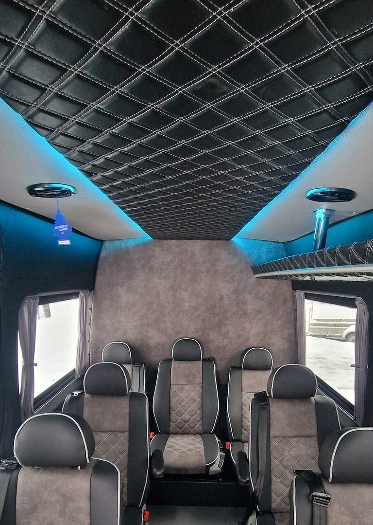 Wnętrze busa z pikowaną tapicerką i niebieskim oświetleniem LED.