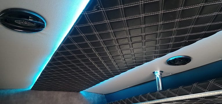 Wnętrze busa z pikowaną tapicerką i niebieskim oświetleniem LED.