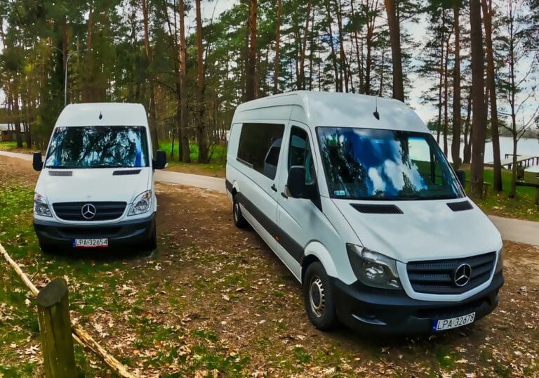 Ośmioosobowe busy Mercedes zaparkowane w lesie nad jeziorem