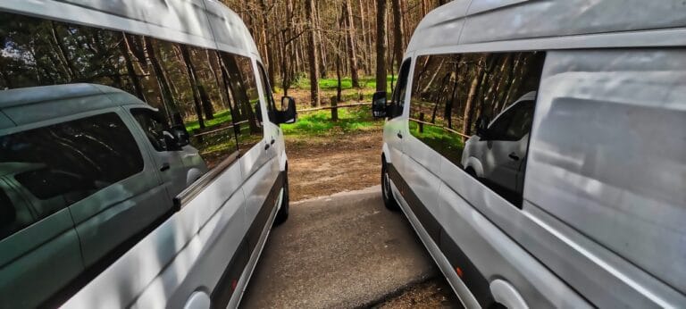 Dwa busy zaparkowane r&oacute;wnolegle w lesie